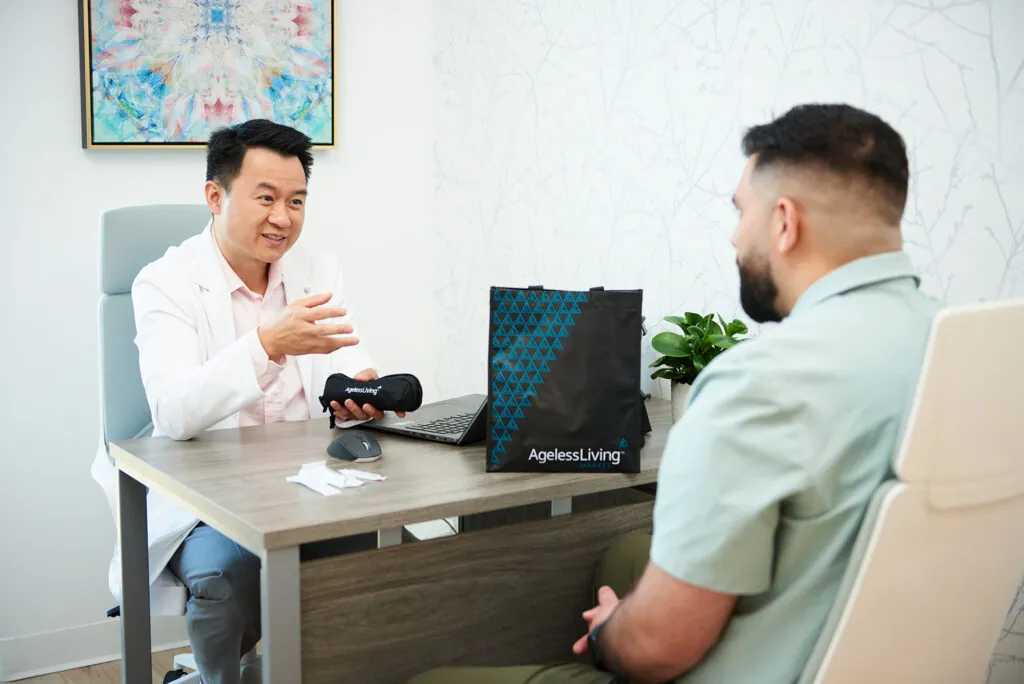 A male patient in consultation with an Ageless Living physician at his desk